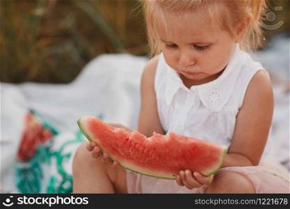 Child eating watermelon in the garden. Kids eat fruit outdoors. Healthy snack for children. Little girl playing in the garden holding a slice of water melon. Kid gardening.. Child eating watermelon in the garden. Kids eat fruit outdoors. Healthy snack for children. Little girl playing in the garden holding a slice of water melon. Kid gardening