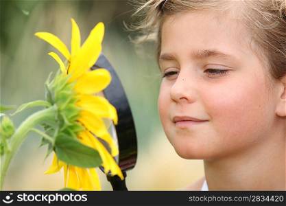 Child examining a sunflower with a magnifying glass
