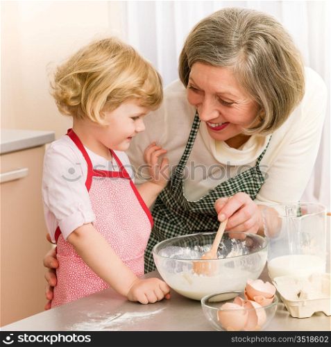 Child girl and grandmother baking cake stir dough