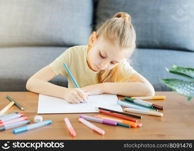 Child girl drawing with colorful pencils at home. Ecology concept, painting earth. 