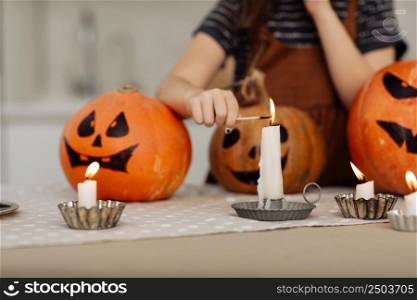child girl lights a candle for Halloween. little girl in witch costume with carving pumpkin with a face made by child. Happy family preparing for Halloween. selective focus.. child girl lights a candle for Halloween. little girl in witch costume with carving pumpkin with a face made by child. Happy family preparing for Halloween. selective focus