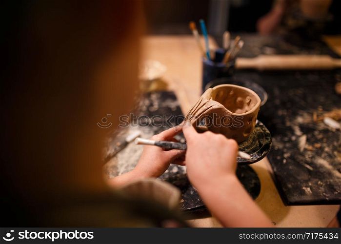 Child girl making a cup from red clay at pottery workshop.. Child girl making a cup from red clay at pottery workshop