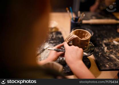 Child girl making a cup from red clay at pottery workshop.. Child girl making a cup from red clay at pottery workshop