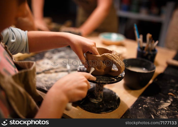 Child girl making a cup from red clay at pottery workshop.. Child girl making a cup from red clay at pottery workshop