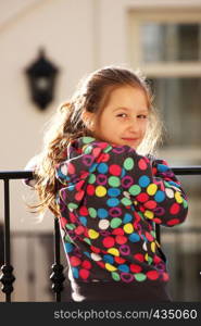 child girl standing on a balcony and looking to the street