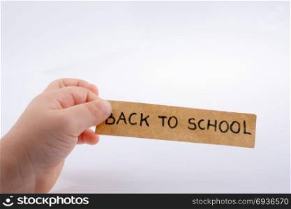 Child hand holding a back to school title on a notebook
