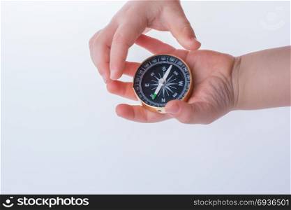 Child hand holding a compass on a white background