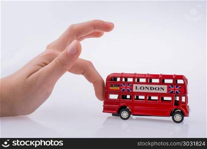 Child hand playing with London double decker bus model on white background. London Bus and hand