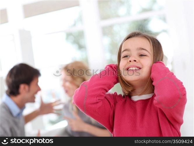 Child hiding her ears from parent&acute;s fight