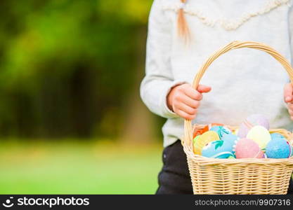 Child holding a basket with easter eggs. Closeup basket full of colorful Easter eggs in kids hands