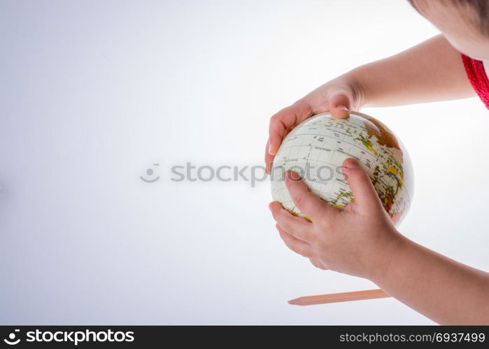 Child holding a globe and a pen in on a white background