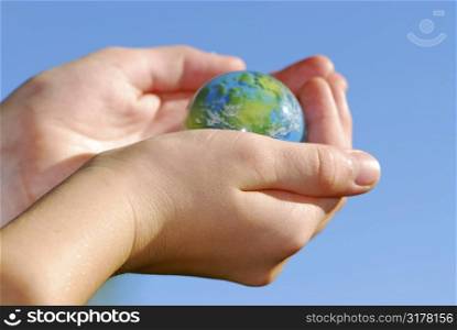 Child holding a globe in hands on blue background