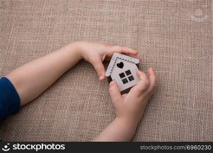 Child holding a model house on a canvas. Child holding a model house on a linen canvas