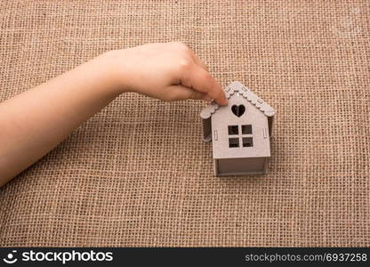 Child holding a model house on a linen canvas