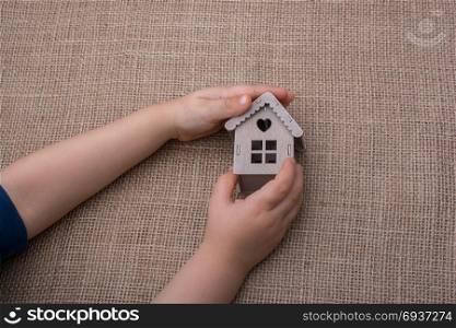Child holding a model house on a linen canvas