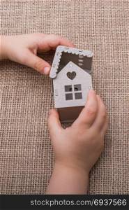 Child holding a model house on a linen canvas
