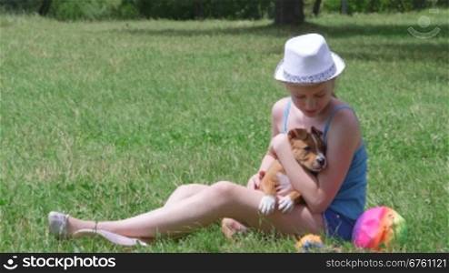 Child holding american staffordshire terrier puppy dog on a grass