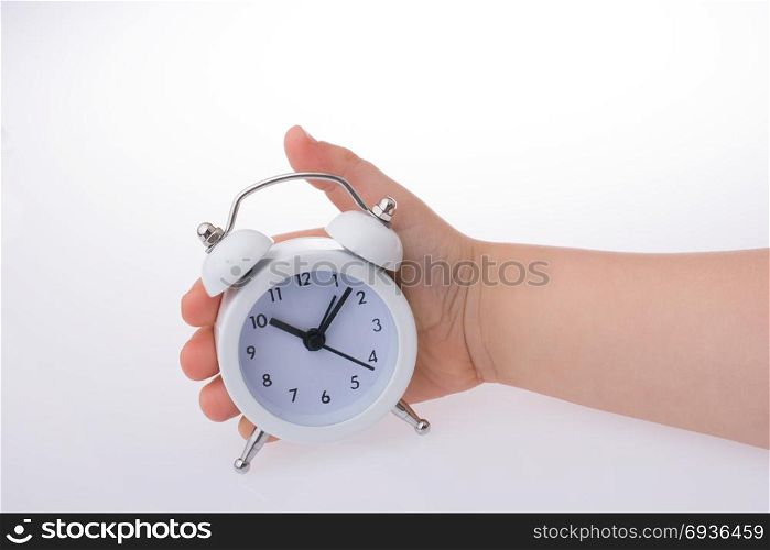 Child holding an alarm clock k on white background
