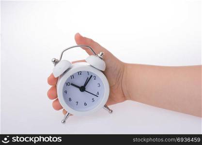 Child holding an alarm clock k on white background