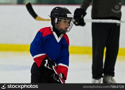 Child ice hockey player at practice with coach watching on