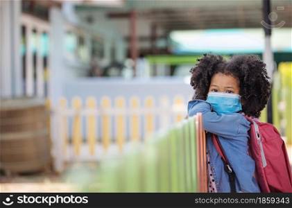 Child in face mask going at reopen school after covid-19 quarantine and lockdown. It is new normal for protection and prevention while outbreak of coronavirus or flu. Kids back to school concept.