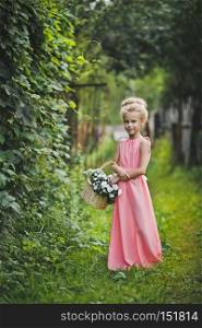 Child in pink dress walks in the garden.. Portrait of a girl with beautiful hair and long pink dress 6589.