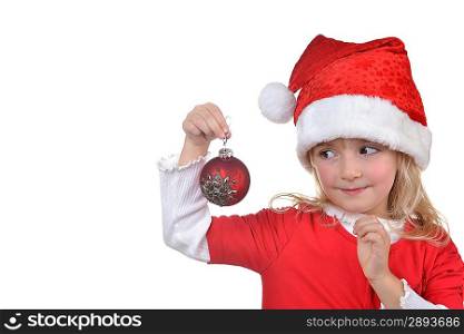 child in santa hat holding christmas decorations in hand