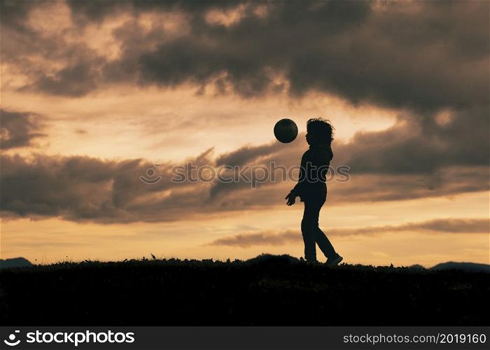 Child in silhouette dribbles with soccer ball