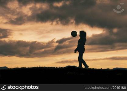 Child in silhouette dribbles with soccer ball