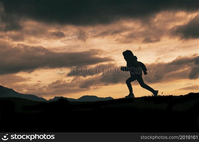 Child in silhouette while running on a meadow
