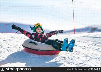 Child in Snow Tube Sledding Downhill. Child in Snow Tube
