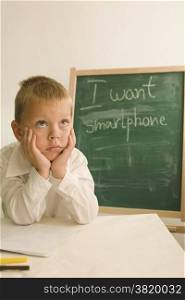 child is seated in front of a board with the inscription smartphone