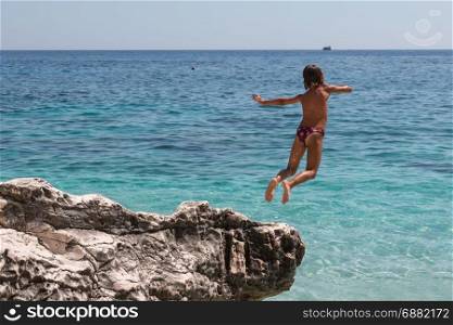 Child Jumping from Cliff into Crystalline Sea in Summertime