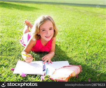child kid girl doing homework smiling happy lying on grass garden with flowers