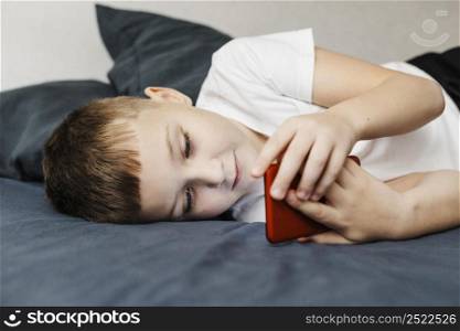 child laying bed using mobile phone side view