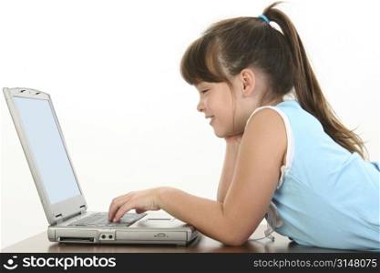 Child laying down working on laptop. Casual school clothes.