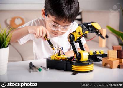 Child learning repairing getting lesson control robot arm, Happy Asian little kid boy using screwdriver to fixes screws robotic machine arm in home workshop, Technology future science education concept