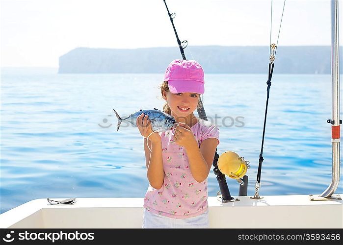 child little girl fishing in boat holding little tunny tuna fish catch with rod and trolling reels