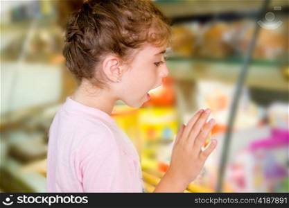 child little girl looking in food shop display excited with sweets