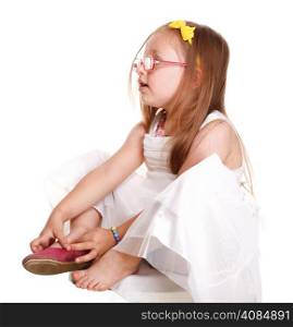 child little girl tries to put on her shoes isolated on white background