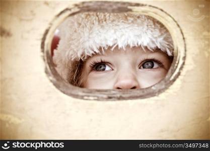 Child look out of hole in wooden background. Shallow depth of field