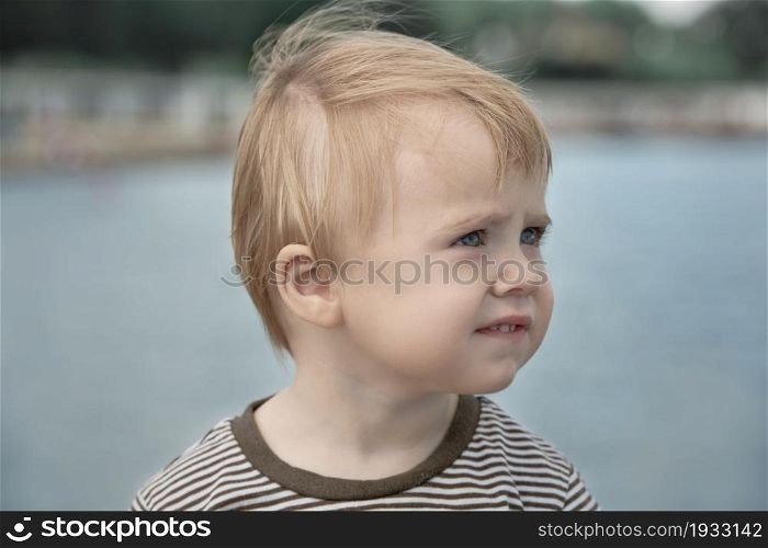 Child looks away head portrait on seashore blurred background