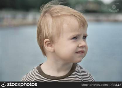 Child looks away head portrait on seashore blurred background