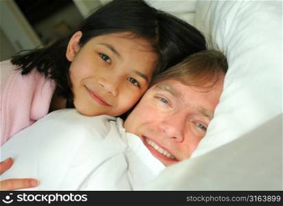 Child lying with parent in bed