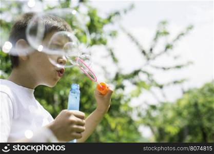 Child makes bubbles. Green park