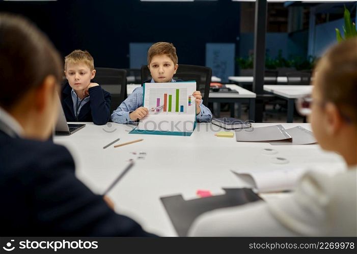 Child office worker present analytics and income forecast. Children IT group on business meeting. Child worker present analytics and income forecast