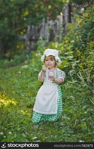 Child on a walk through the garden.. Girl in dress and hat walking in the garden 4663.
