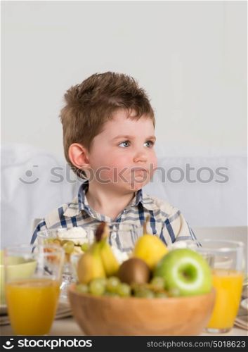 Child on breakfast - looking capricious while sitting at home near table