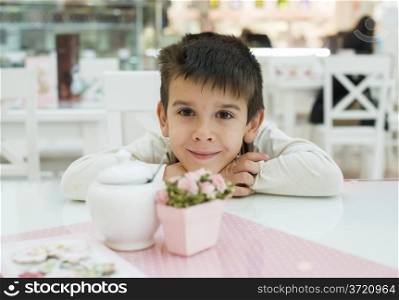Child on table in confectionery. Close up pink table