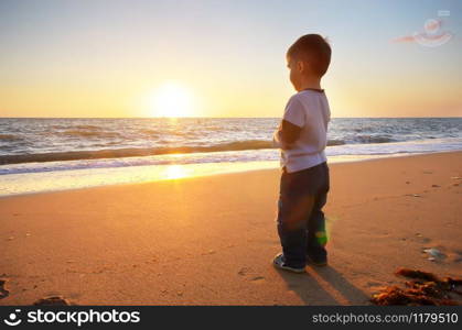 Child on the beach looking on the sea sunset. Conceptual scene.